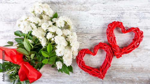 A bouquet of white roses with a red ribbon and two frames of red rattan hearts for an inscription or photo. Valentine's day, wedding, love. Place for text, top view, flat lay, copy space.