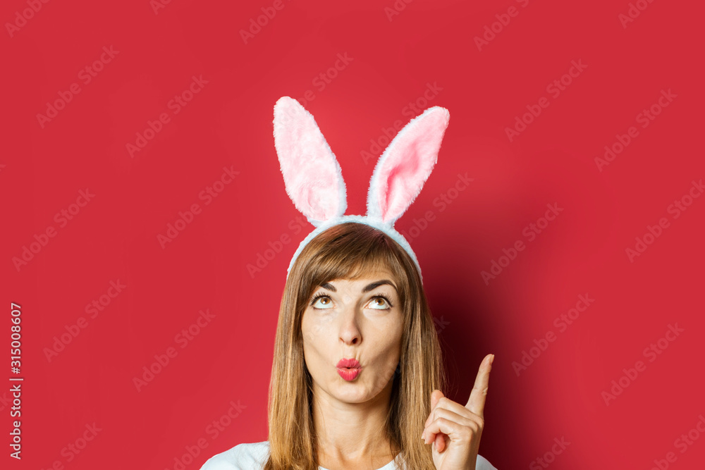 Young girl with rabbit ears on a pink background. Easter concept, easter bunny