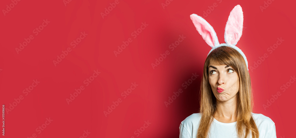 Young beautiful woman with rabbit ears on a pink background. Easter concept