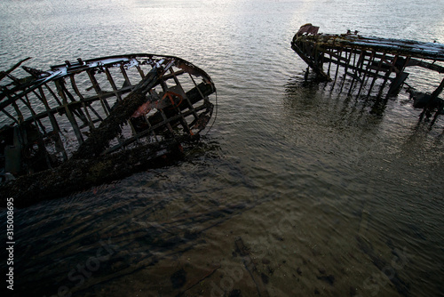 abandoned  already rotten skeletons of ships lying on the coast of the Arctic ocean against the background of a pink sunset