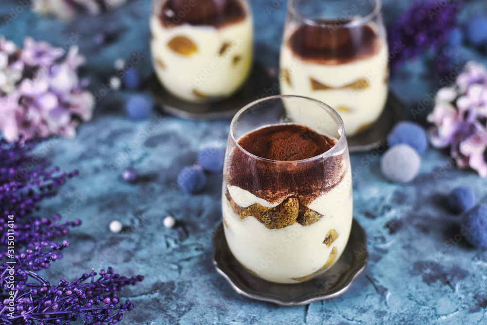 Homemade coffee flavoured layered Italian mascarpone cheese Tiramisu dessert topped with cocoa in glasses Homemade coffee flavoured layered Italian mascarpone cheese Tiramisu dessert topped with cocoa in glasses