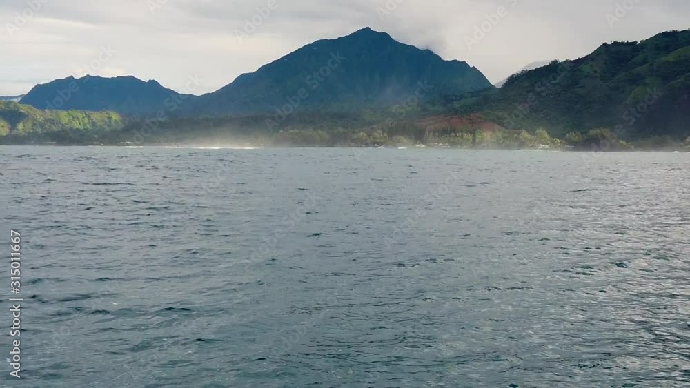 HD 120fps Hawaii Kauai Boating on the ocean floating right to left with mountain and hills in cloudy distance with boat spray in foreground, slow left to right pan HD 120fps Hawaii Kauai Boating on the ocean floating right to left with mountain and hills in cloudy distance with boat spray in foreground, slow left to right pan