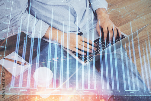 Forex graph with businessman working on computer in office on background. Concept of analysis. Double exposure.