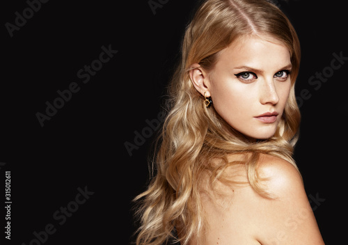 Close-up portrait of beautiful model with long blond hair on black background