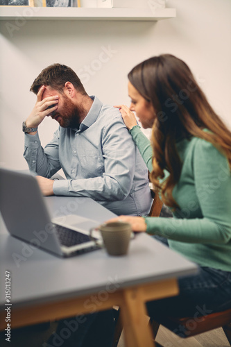 Young male having headache at work. His colleague trying to help. 