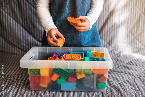 Little girl cleaning up the toy box at home. Child's space organization.