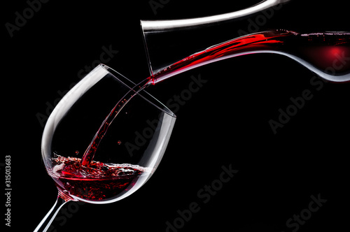 Red wine is poured into a wine glass on a black background.