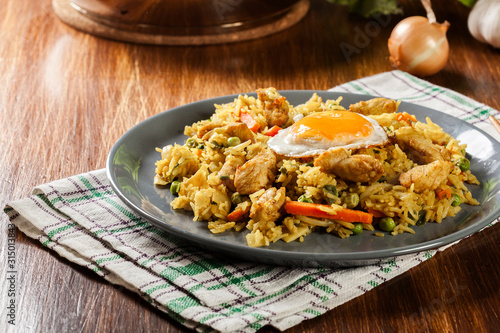 Fried rice nasi goreng with chicken egg and vegetables on a plate.