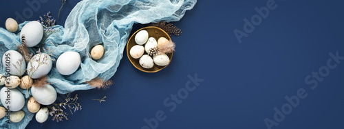 Easter banner with painted eggs and napkin on dark blue backround. Top view, flat lay with copy space. © Olga Zarytska
