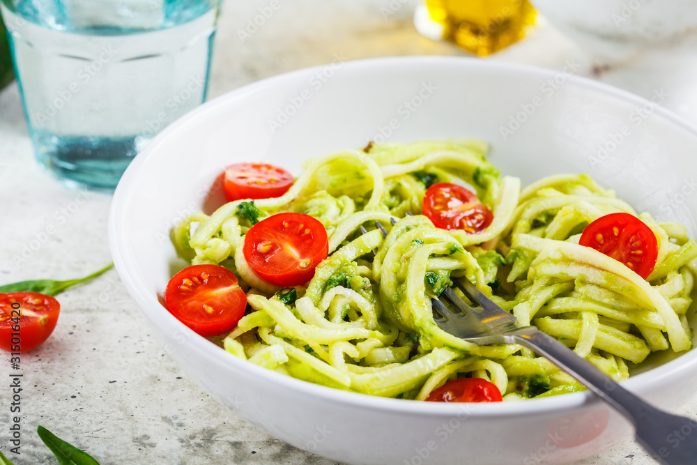 Zucchini pasta with pesto, avocado and tomatoes in white plate. Raw vegan food concept. Zucchini pasta with pesto, avocado and tomatoes in white plate. Raw vegan food concept.