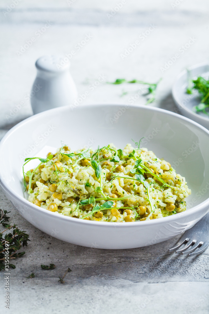 Green risotto with broccoli, green peas and sprouts in white plate. Healthy vegan food concept. Green risotto with broccoli, green peas and sprouts in white plate. Healthy vegan food concept.