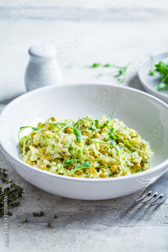 Green risotto with broccoli, green peas and sprouts in white plate. Healthy vegan food concept.