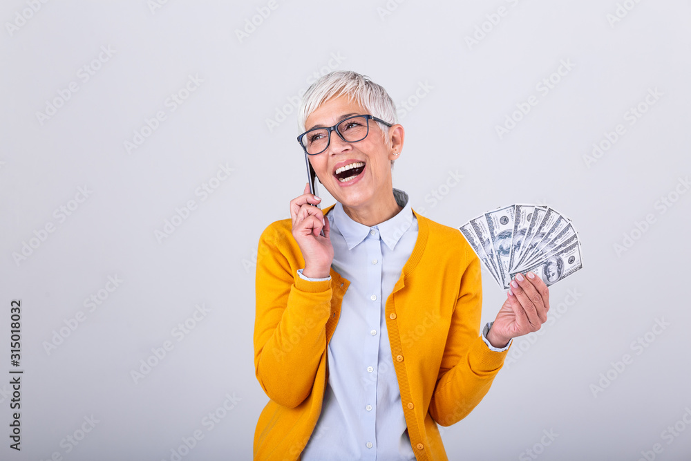 Excited beautiful senior woman talking on her smartphone and holding money, cashback. Finances and people concept, senior woman holding hundreds of dollar money banknotes Excited beautiful senior woman talking on her smartphone and holding money, cashback. Finances and people concept, senior woman holding hundreds of dollar money banknotes