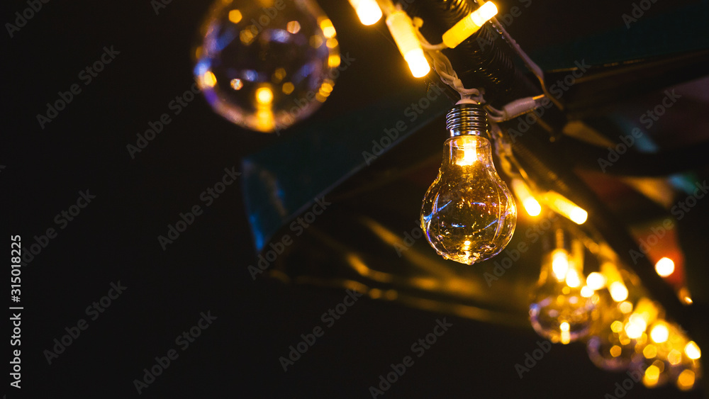 Retro style incandescent light bulb garland as decoration of a city street at night. Lamps on a black background.