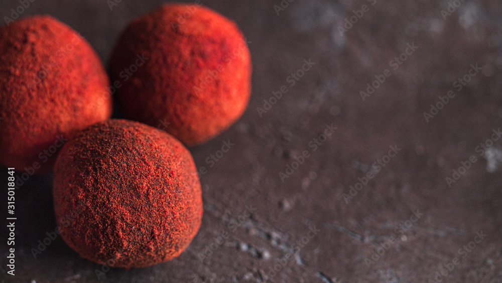 Red homemade truffle coated dry beet powder on dark background. Copy space right for text or design, banner. Red homemade truffle coated dry beet powder on dark background. Copy space right for text or design, banner.