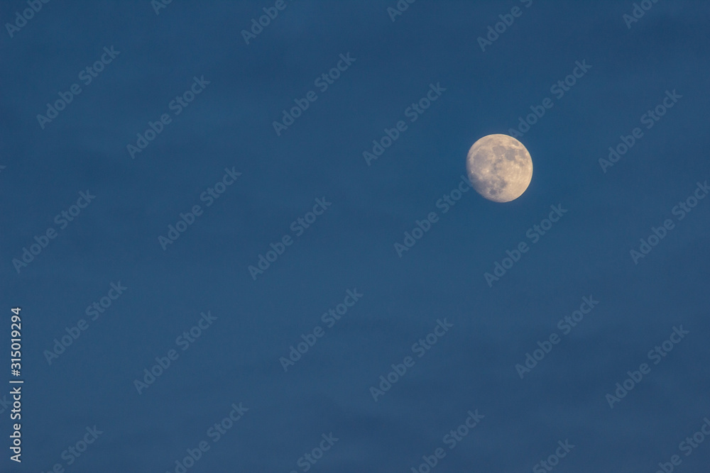 Blue sky with clouds and a round full moon. A beautiful night sky. Moonlight evening light. Blue sky with clouds and a round full moon. A beautiful night sky. Moonlight evening light.