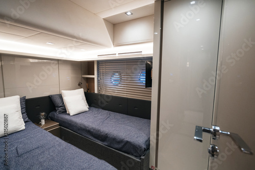 luxury yacht interior: Large sleeping cabins for two passengers. Bed pillows porthole and tv.