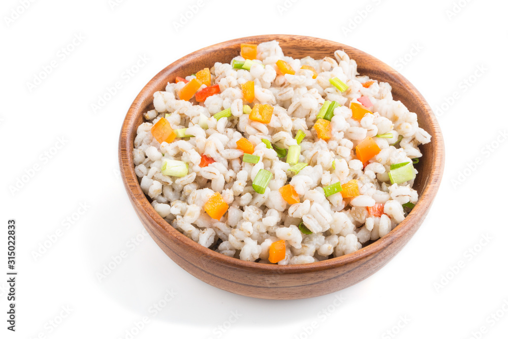 Pearl barley porridge with vegetables in wooden bowl isolated on white background. Side view, close up.