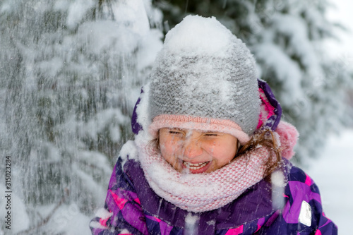 A lot of snow falls on a little girl. Winter walk