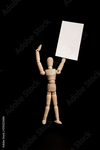 the wooden figure of Gestalt joyfully holds an empty sign for the text and points to it. black background