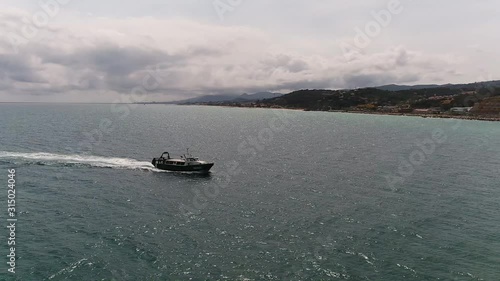 Aerial Shot of a Boat Moving Across Water Near Shore Line on a Calm Clear Day photo