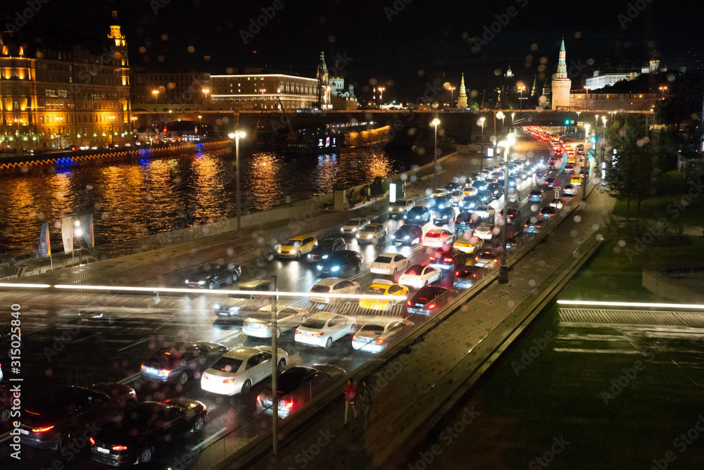 Night traffic of cars in a big city. Evening Moscow. Light from headlights of cars and buildings. The movement of cars on the street.