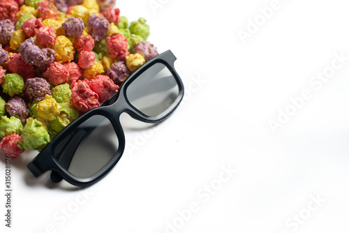 Multicolored fruit flavored popcorn with cinema 3D glasses on pink background. Candy coated popcorn. Top view.