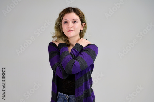 Portrait of a pretty student girl with beautiful curly hair. Concept horizontal photo of a young woman with emotions in a dark jacket standing in front of the camera on a white background.