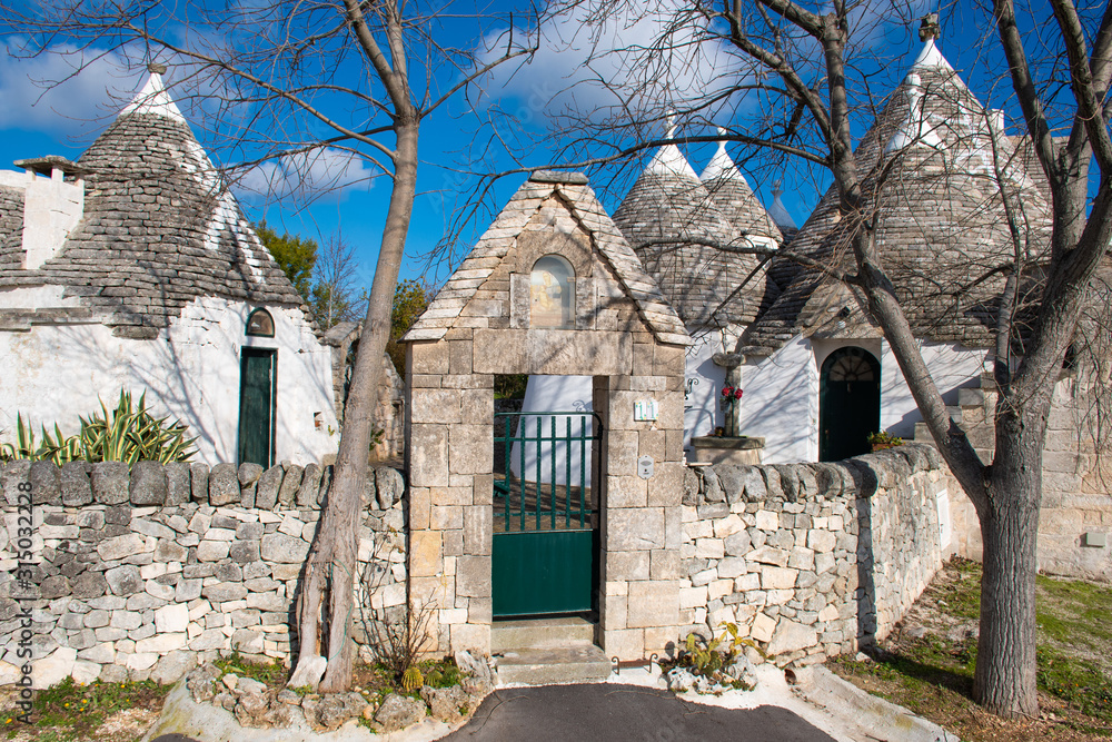 Group of beautiful Trulli with symbols, traditional old houses and old stone wall in Puglia, Italy, Europe