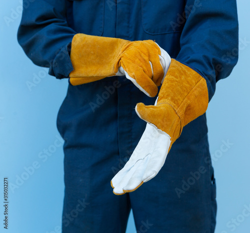 Closeup hands of Asian mechanic wearing leather gloves isolated on blue background