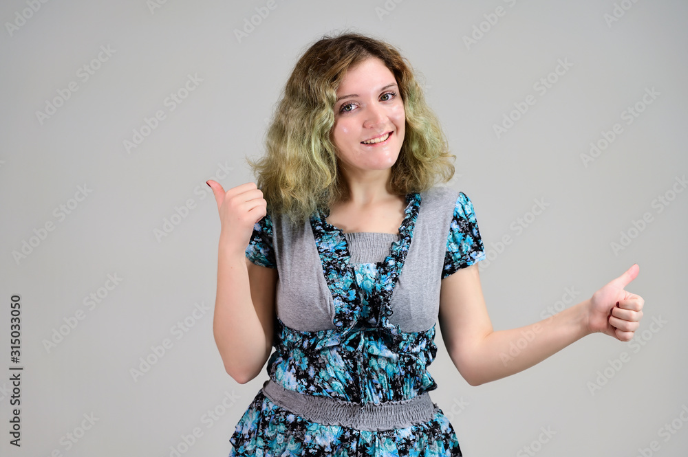 Concept horizontal photo of a young woman with emotions in a turquoise dress stands in front of the camera on a white background. Portrait of a student girl with beautiful magnificent hair. Concept horizontal photo of a young woman with emotions in a turquoise dress stands in front of the camera on a white background. Portrait of a student girl with beautiful magnificent hair.