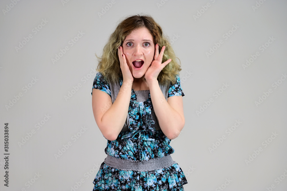 Portrait of a student girl with beautiful magnificent hair. Concept horizontal photo of a young woman with emotions in a turquoise dress stands in front of the camera on a white background. Portrait of a student girl with beautiful magnificent hair. Concept horizontal photo of a young woman with emotions in a turquoise dress stands in front of the camera on a white background.