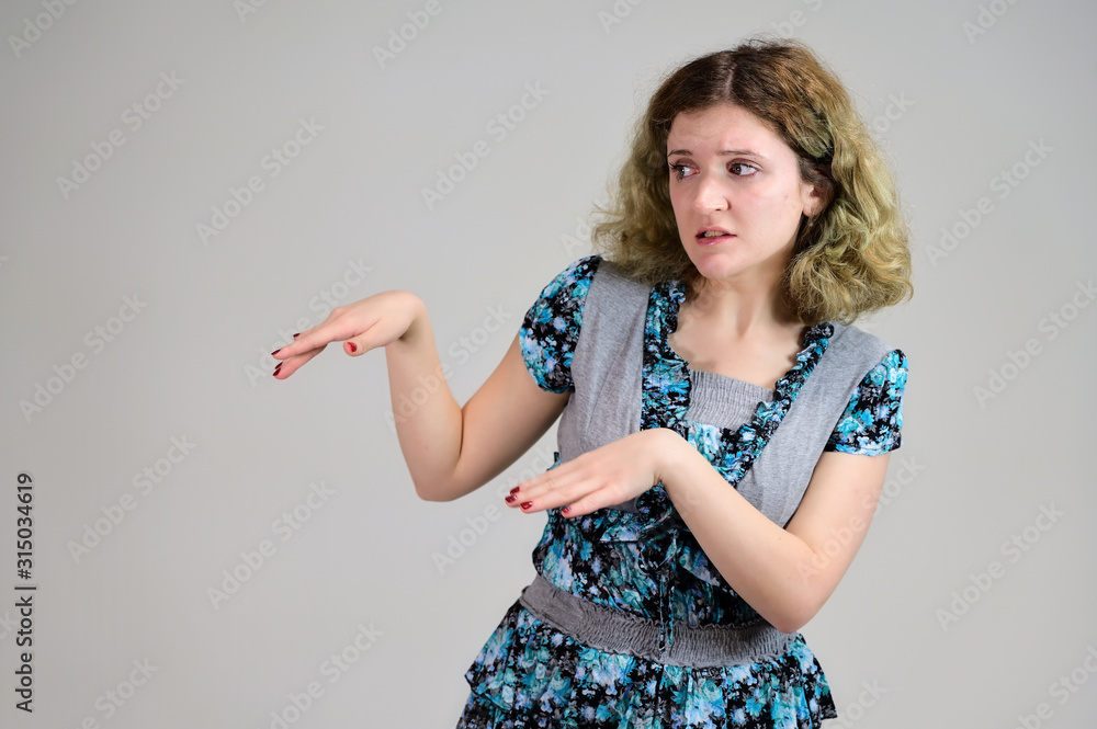 Portrait of a student girl with beautiful magnificent hair. Concept horizontal photo of a young woman with emotions in a turquoise dress stands in front of the camera on a white background. Portrait of a student girl with beautiful magnificent hair. Concept horizontal photo of a young woman with emotions in a turquoise dress stands in front of the camera on a white background.