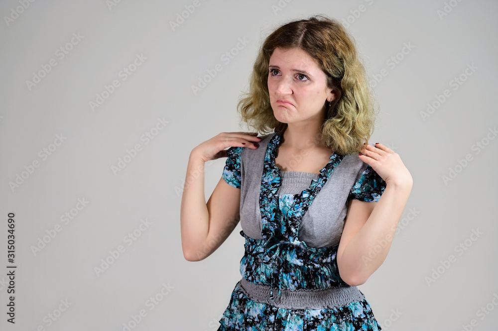 Portrait of a student girl with beautiful magnificent hair. Concept horizontal photo of a young woman with emotions in a turquoise dress stands in front of the camera on a white background. Portrait of a student girl with beautiful magnificent hair. Concept horizontal photo of a young woman with emotions in a turquoise dress stands in front of the camera on a white background.