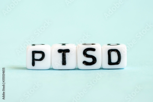 PTSD word written on blocks. Posttraumatic stress disorder inscription on blue background. Medical concept