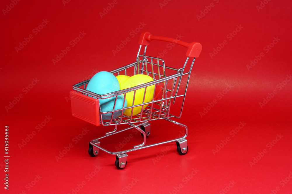Shopping Cart and couple yellow and blue heart on Red background - Shopping stores to buy Love Heart concept - Valentine Day - Find couple lover