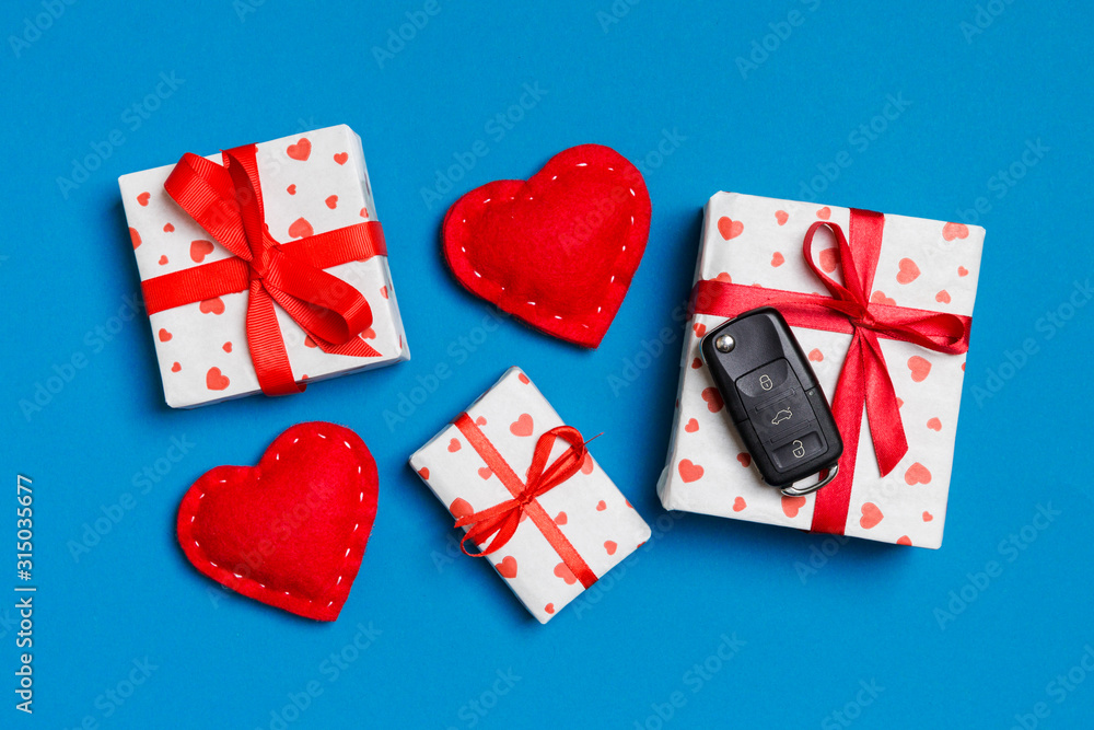 Top view of car key on gift box and red textile hearts on colorful background. Present for Valentine's Day concept Top view of car key on gift box and red textile hearts on colorful background. Present for Valentine's Day concept
