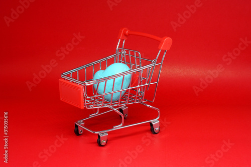 Shopping Cart and single blue heart on Red background - Shopping stores to buy Love Heart concept - Valentine Day - Find couple lover