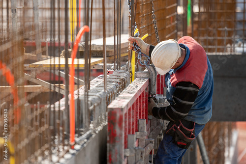 Slika na platnu Male construction worker installing concrete retaining wall rebar on constructio