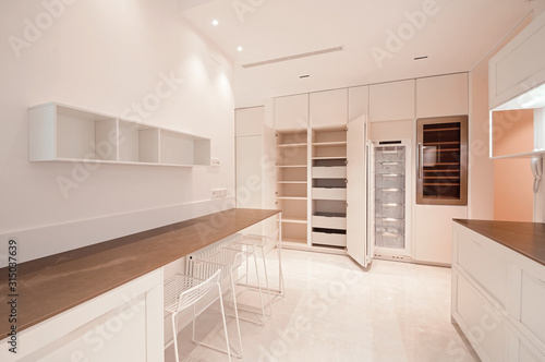 Classic modern kitchen with wooden and white details, minimalistic interior design, modern furniture whith lifting systems, open furniture and open freezer. Kitchen with integrated appliances.