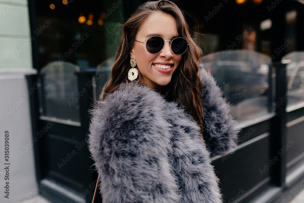 Resilient dark-haired girl walking in city in autumn morning. Outdoor portrait of pretty curly woman smiling on city background Resilient dark-haired girl walking in city in autumn morning. Outdoor portrait of pretty curly woman smiling on city background