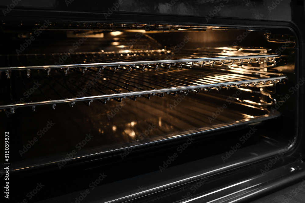 Ajar or open hot oven close-up. Backlit electric grill for cooking bbq in kitchen.