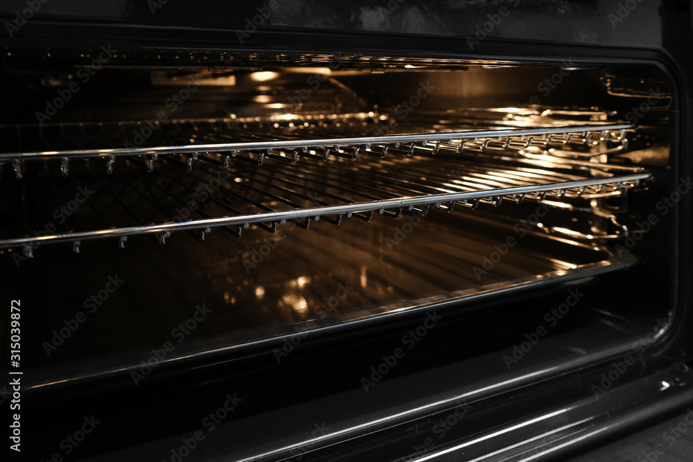 Ajar or open hot oven close-up. Backlit electric grill for cooking bbq in kitchen. Ajar or open hot oven close-up. Backlit electric grill for cooking bbq in kitchen.