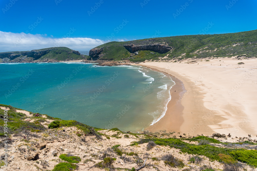 Aerial drone view of empty sandy beach and green grassy hills coastline