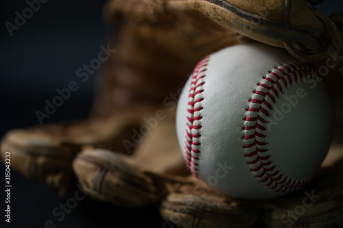 Baseball in a glove on black background.