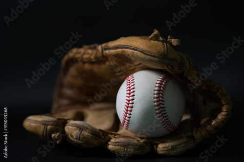Photography Baseball in a glove on black background.