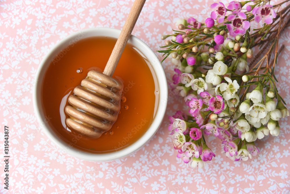 manuka honey and blooming manuka flower tree on a pink background