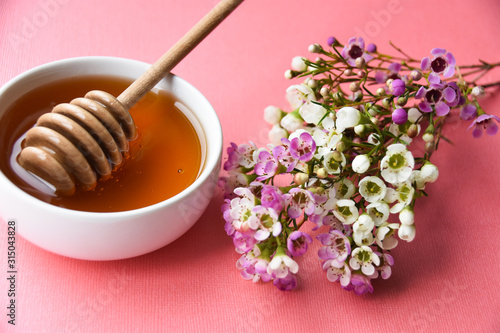 manuka honey and blooming manuka flower tree on a pink background