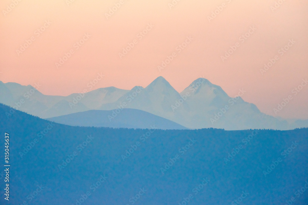 Belukha Mountain is the highest peak of the Altai Mountains. View of snow-capped peaks in the sunset light. Blur effect. Katon-Karagay National Park. Kazakhstan.