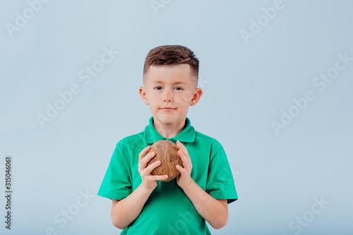 boy with coconut in hand. isolated on blue background, copy space, in studio,